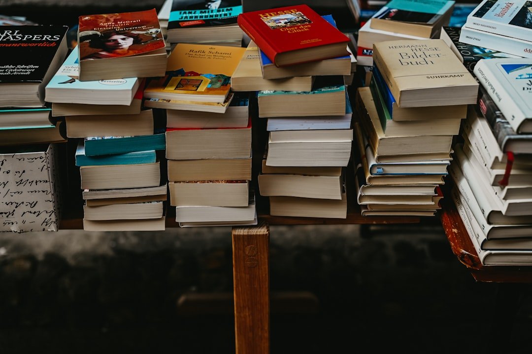 a-pile-of-books-sitting-on-top-of-a-wooden-table-egt5-6j410c