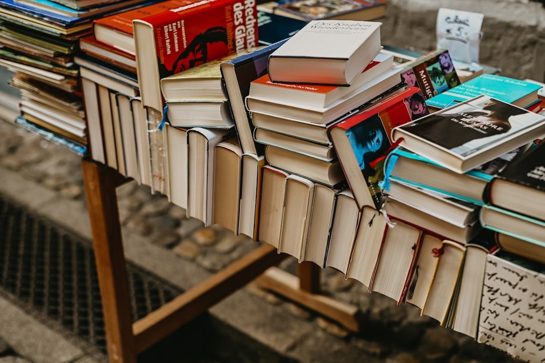 a-pile-of-books-sitting-on-top-of-a-wooden-table-ozucu-0umti